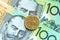 One dollar australian coins on one hundred banknote background