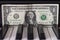 One dollar banknote lying on the piano keys.