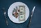 One dollar lying on the plate with fork and knife. No money photo. Poor people idea. Dimes and cents coins. Small salary and