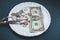 One dollar lying on the plate with fork and knife. No money photo. Poor people idea. Dimes and cents coins. Small salary and