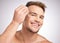 One drop and youll look amazing. Studio shot of a young man applying serum to his face against a grey background.