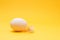 One egg and one gentle feather on yellow background. minimalist design
