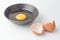 One egg yolks in black bowl and broken egg shells