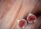 One fig sliced in half on on wooden board background. Focus is on the sliced fig
