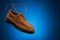 One flying leather boat shoes of wheat or brown nubuck with flying laces on a blue background