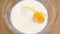 One fresh chicken egg is broken in plate with milk