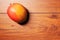 One fresh ripen mango fruit on a brown wooden surface, Flat lay, copy space