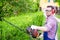 One gardener shaping hedge using hedge trimmer