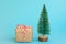 One gift box wrapped in craft paper tied with red white ribbon Christmas trees on blue background. New Year corporate presents