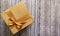 One gift wrapped in brown paper with a luxurious bow on a wooden background