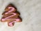 one ginger herringbone-shaped cookie, with pink icing sugar, grey background. ginger biscuits in herringbone form with pink icing