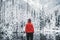 One girl hiker stands in front of a winter lake looking to the snowy landscape. Rear view