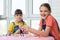 One girl laughs cheerfully, the other makes faces, children play a board game