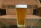 One glass of chilled beer isolated on the table with blurry empty chair in background