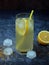 One glass of cold homemade lemonade with lemon slices, ice cubes, brown sugar and straws