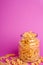 One glass jar with variety of uncooked golden wheat pasta on minimal pink background, angle view macro
