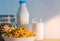 One glass of milk and milk bottle with blank label put on wood table near bowl of cereal with spoon. Calcium food breakfast