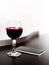 One glass of red wine and a mobile phone on brown wodden table and white blurred wall background. Alcohol drink and smartphone on