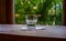 One glass of water stands on a white napkin on a wooden table near a window overlooking the avenue with blooming chestnut trees