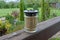 One gray glass jar with a decorative candle stands on a brown board on the veranda