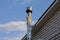 One gray metal chimney pipe on a white brick wall of the attic