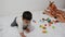 One and a half years old baby boy playing with lego blocks and soft toy dear on the bed