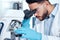 One handsome young mixed race man with a dark beard wearing gloves and a labcoat and looking at medical samples on a