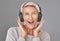 One happy mature woman isolated against a grey background in a studio and wearing headphones to listen to music. Smiling