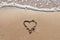 One Heart Drawn in the Sand on a Beach.soft wave of the sea.Romantic love. true love.Beige beach