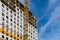 One high-rise crane against a house and sky during the construction phase. Industry concept for low-income young families.