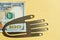 One hundred American dollar bill, holding by metal hand on the golden background. Conceptual photo, minimalistic design