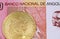 A one hundred Angolan kwanza bank note with a golden physical Bitcoin