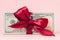 One hundred dollars gift wraped with a red ribbon on pink background
