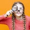 One Intelligent Caucasian Girl in Glasses And Coral Knitted Sweater Holding Big Magnifying Glass While Searching And Looking