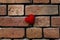 One knitted red heart on a crumbling old red brick textured wall