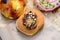 One large freshly deep fried donut coated with chocolate and colored candies, on a brown paper, in display for sale at a street fo