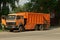 One large orange truck a garbage collector