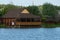 One large wooden brown house with an open veranda over the lake water