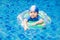 One little girls swimming in the pool with rubber ring, having f