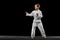 One little kid, boy, taekwondo athlete posing isolated over dark background. Concept of sport, education, skills