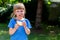 One little school age girl eating a single slice of bread with butter outdoors, copy space. Young kid taking a bite of a bread