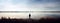One lonely man standing on the side of a vast lake, gazing into the horizon, looking at the calm lake