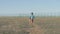 One lonely poor dirty little boy with toy walking along desert near state border with fence and razor barbed wire head down