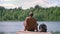 One man with a backpack rests sitting on a pier on the shore of a lake in the woods. The tourist rests after a long walk