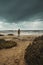 One man standing against cloudy epic background at the beach. Ocen sea and bad weather in background. Climate change for global