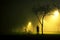 One man is standing and holding the bicycle in foggy and mysterious park.