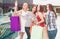 One more picture of fabulous and marvelous girls standing in mall with bags and posing. They are looking up, smiling and