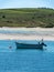 One motorboat is anchored near the picturesque shores of southern Ireland. Seaside landscape. Green hilly coast, boat on seashore