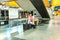 One Muslim female wearing hijab, one Asian male teen sitting on bench in subway station