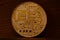 One new golden physical bitcoin is lies on dark wooden backgound, close up. High resolution photo. Cryptocurrency mining concep